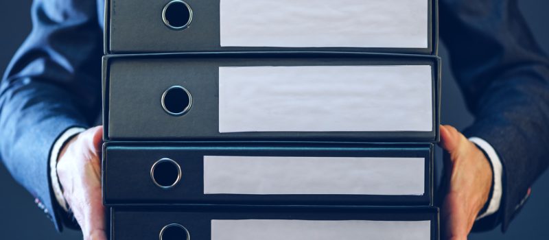 Businessman with corporate files in four document binder, blank label as copy space